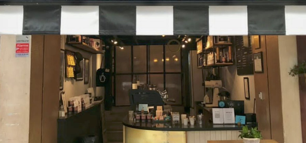 The counter and espresso machine at Café ao Léu, seen from the striped awning outside
